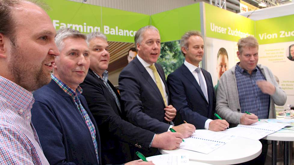Foto: Mathias Teepker (l), Martin Demann (2e van L) en Andreas Maas (geheel rechts) tekenen, onder toeziend oog van Frans Stortelder (midden), op de Eurotier de overeenkomst die hen aan het Good Farming Balance bindt.