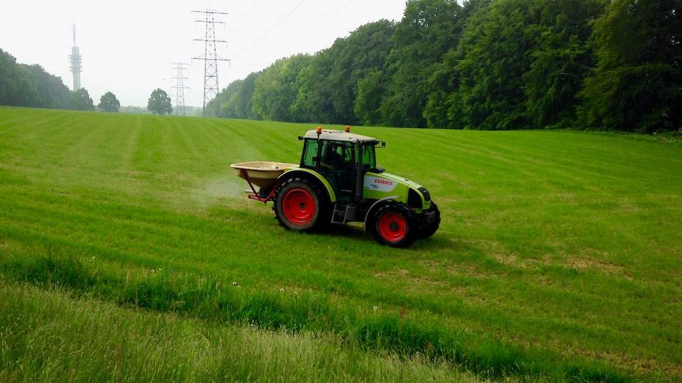 Een veehouder strooit kunstmest op een heuvelachtig perceel in Arnhem-Noord.