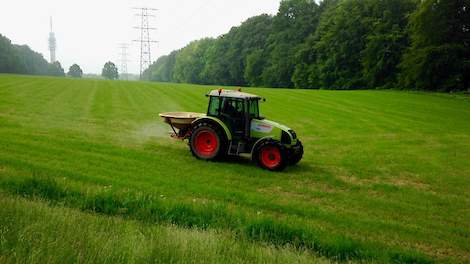 Een veehouder strooit kunstmest op een heuvelachtig perceel in Arnhem-Noord.