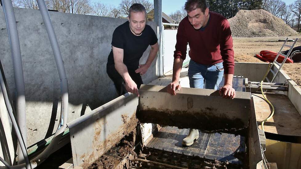 Ontwikkelaar Theo Tangelder (links) en Rob Nieuwenhuis (rechts) van het Zonvarken bij het eindstation van het mestsysteem waar de mest van de tegels wordt afgeschoven.