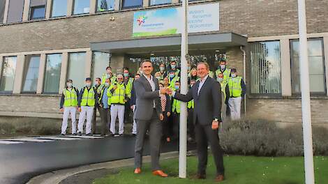 Arnoud van den Berg (President FrieslandCampina Trading) en Robert van Ballegooijen (COO Royal A-ware) hijsen de A-ware vlag op de plant in Aalter.