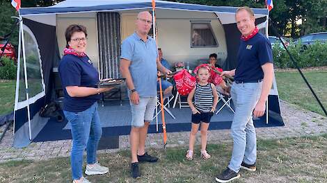 Melkveehouders Dianne Vedders (links) en Huub Kamphuis (rechts) overhandigen een knapzak aan vakantieganger André Kuik (midden).