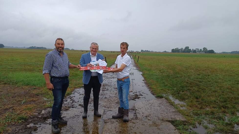 Johannes Post (rechts) presenteert samen met collega-melkveehouder Jaco Visscher (links) de oplossing op een presenteerblaadje aan gedeputeerde Ten Bolscher.