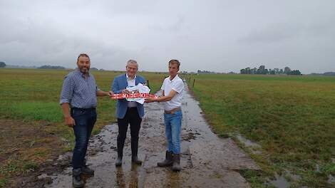 Johannes Post (rechts) presenteert samen met collega-melkveehouder Jaco Visscher (links) de oplossing op een presenteerblaadje aan gedeputeerde Ten Bolscher.