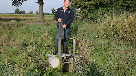 Janus Scheepers staat bij een stuw. Deze techniek draagt bij aan waterconservering op agrarische percelen.