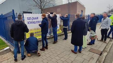 Boeren hangen de feestelijke banner op aan het hek.