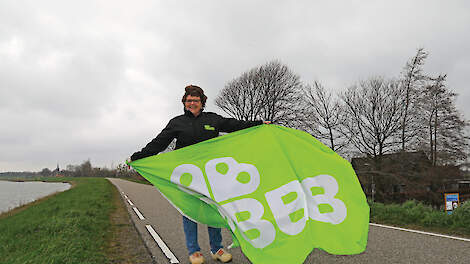 Een trotse Ingrid de Sain met de vlag van de BBB op de dijk voor het melkveebedrijf in het West-Friese Schellinkhout.