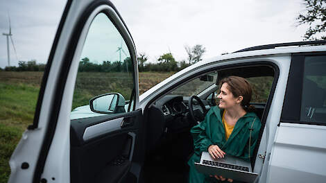 Boeren ondernemer zit in auto met laptop op schoot.
