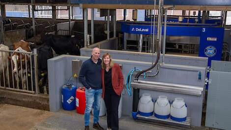 Roland en Janette Kooiker bij twee van de vier nieuwe melkrobots. Om de robots passend te maken in de bestaande stal, is er gekozen voor de zogeheten ‘kassaopstelling’.