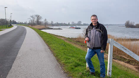 Melkveehouder Gerrit de Jong boert tussen de Lek (achter hem op de foto) en de Merwede in de polder van Meerkerk.