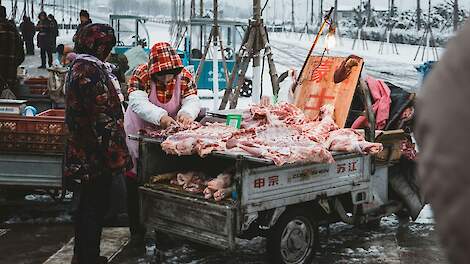 Een straathandelaar verkoopt varkensvlees in China.