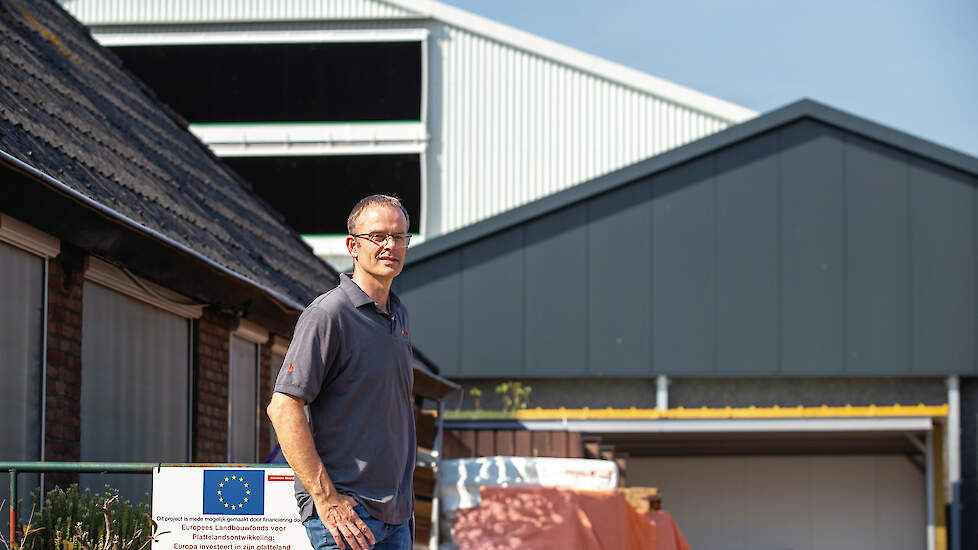 Vleeskuikenhouder Rob Wingens bij het woonhuis met op achtergrond nieuwe Eco Air Care vleeskuikenstal.