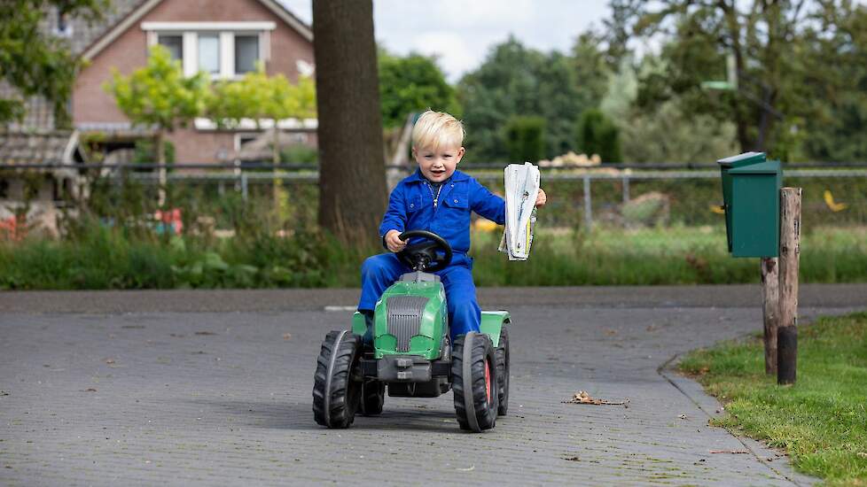 Kindje op speelgoedtrekker in overal met een vakblad in de hand.