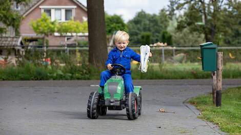 Kindje op speelgoedtrekker in overal met een vakblad in de hand.