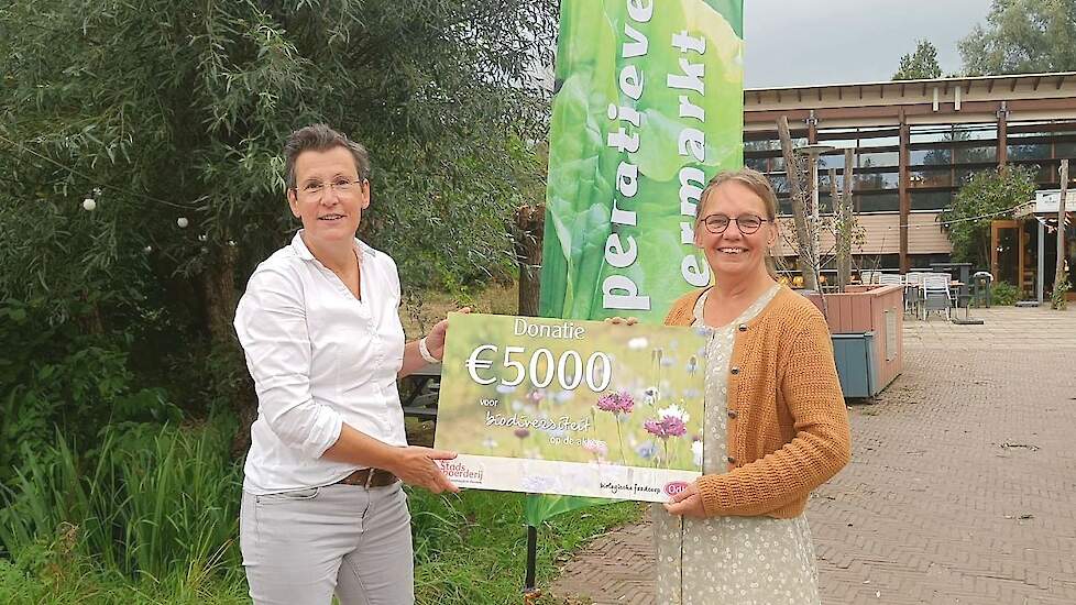 Merle Koomans van den Dries, directeur van Odin (links), geeft een cheque van 5.000 euro aan Tineke van den Berg van Stadsboerderij Almere.