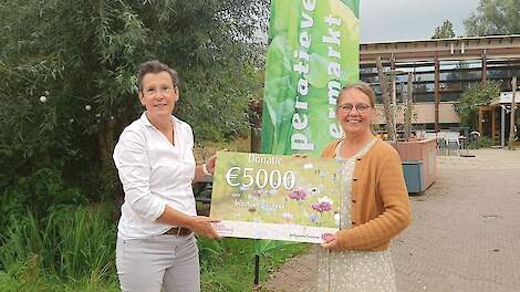 Merle Koomans van den Dries, directeur van Odin (links), geeft een cheque van 5.000 euro aan Tineke van den Berg van Stadsboerderij Almere.