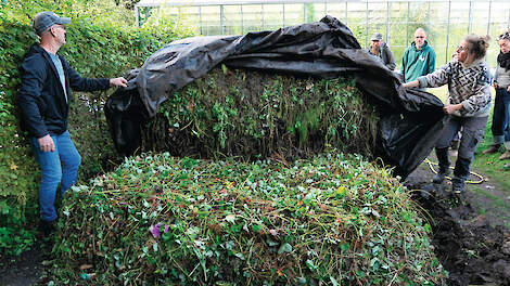 Tuinder Esther Kuiler (rechts) dekt zorgvuldig de nieuwe bokashihoop toe met een zeil, voor zuurstofvrije fermentatie.