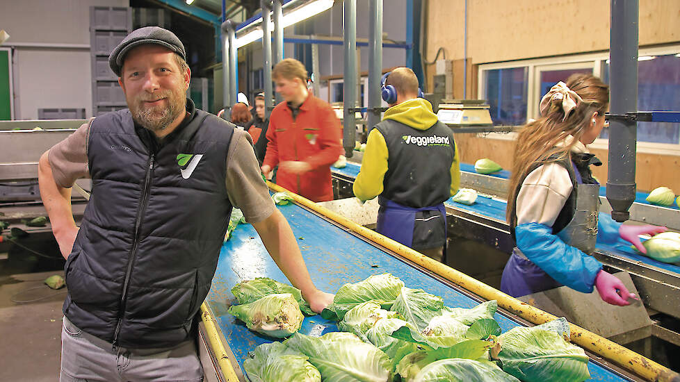Dorus Droog naast een transportband met kroppen sla