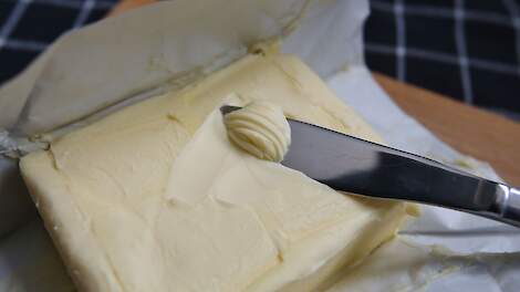 Een pakje roomboter met een mespunt vol boter.