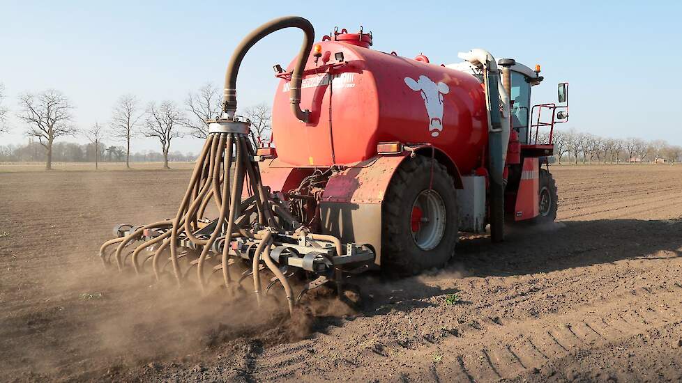 Een bemester rijdt drijfmest uit op een bouwland.