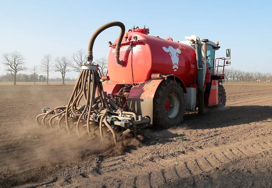Een bemester rijdt drijfmest uit op een bouwland.