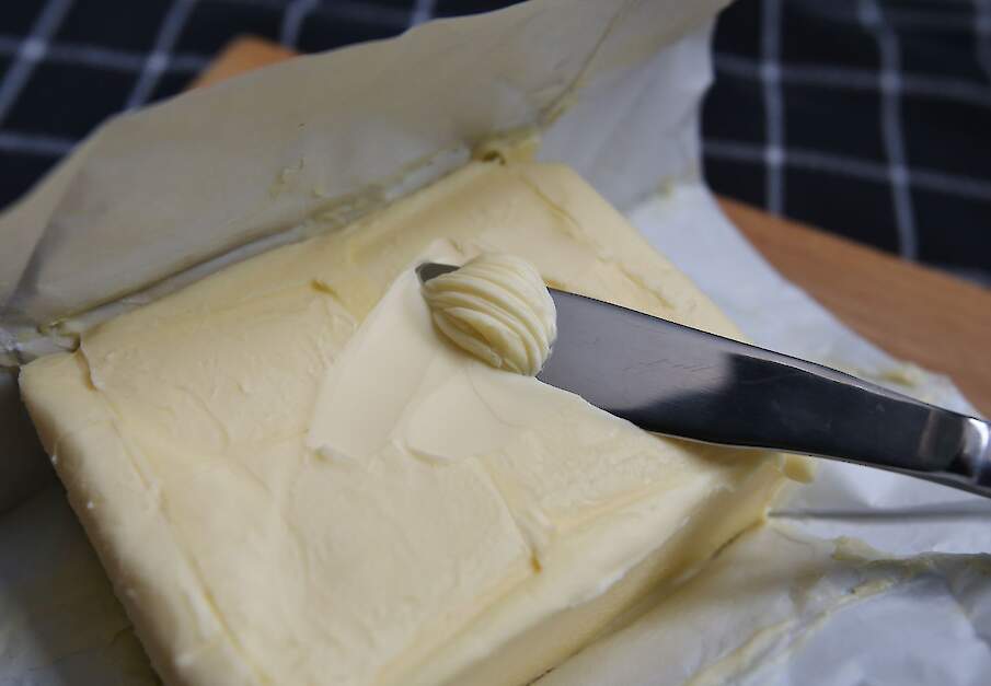 Een mes schraapt over een pakje roomboter.