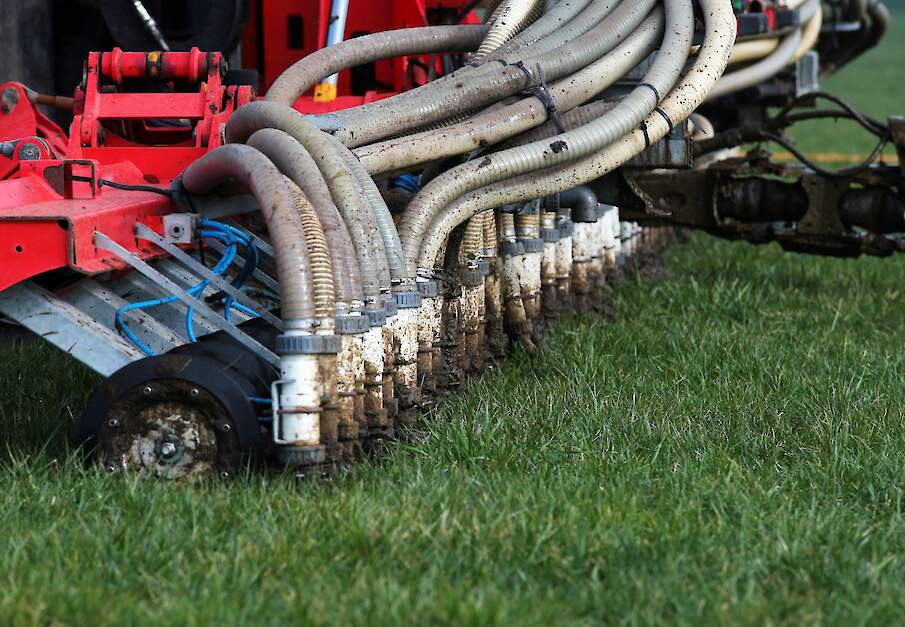 Een zodebemester rijdt rundveedrijfmest uit op grasland.