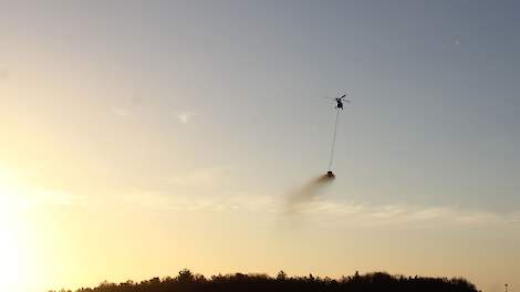 steenmeel strooien met helikopter boven natuur