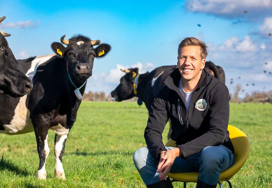 Harm Rijneveld tussen een koppel koeien in de wei