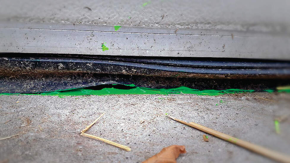 Groene fluorescentiegel bij een kromme rubber van een roldeur om waterlekkage naar binnen zichtbaar te maken.