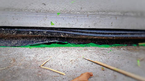 Groene fluorescentiegel bij een kromme rubber van een roldeur om waterlekkage naar binnen zichtbaar te maken.
