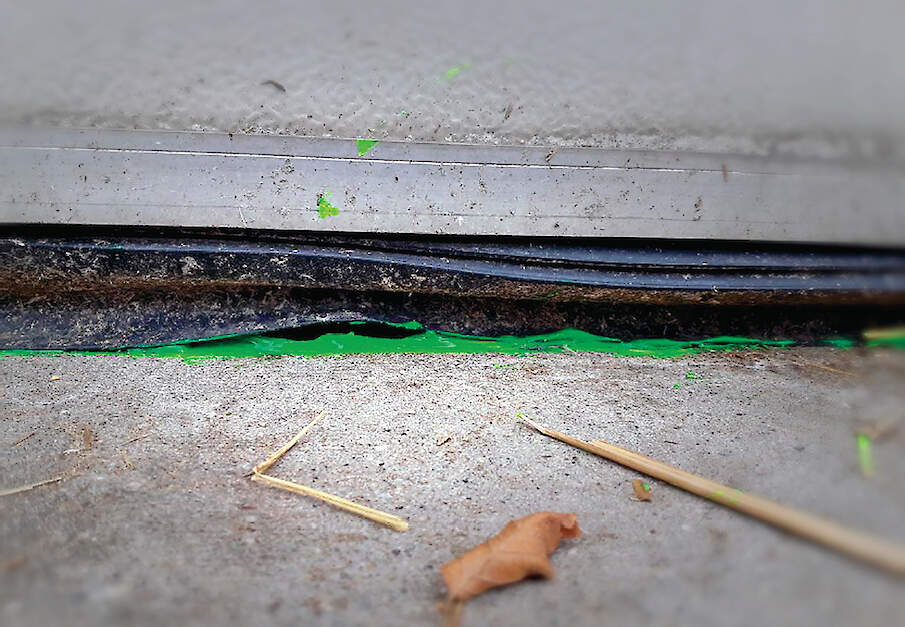 Groene fluorescentiegel bij een kromme rubber van een roldeur om waterlekkage naar binnen zichtbaar te maken.
