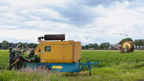 Boer beregent perceel met pomp en haspel