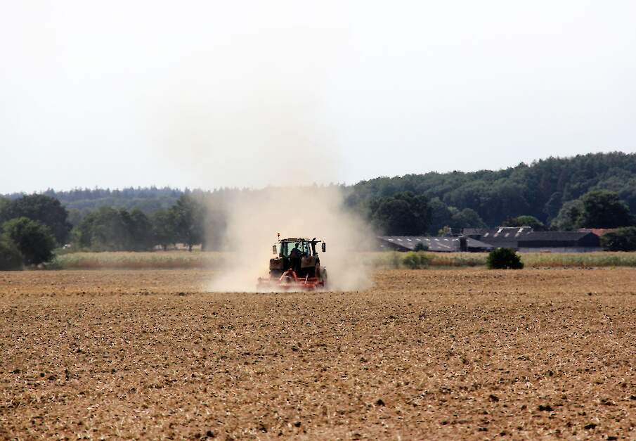 Een trekker te minden van een stofwolk aan het werk