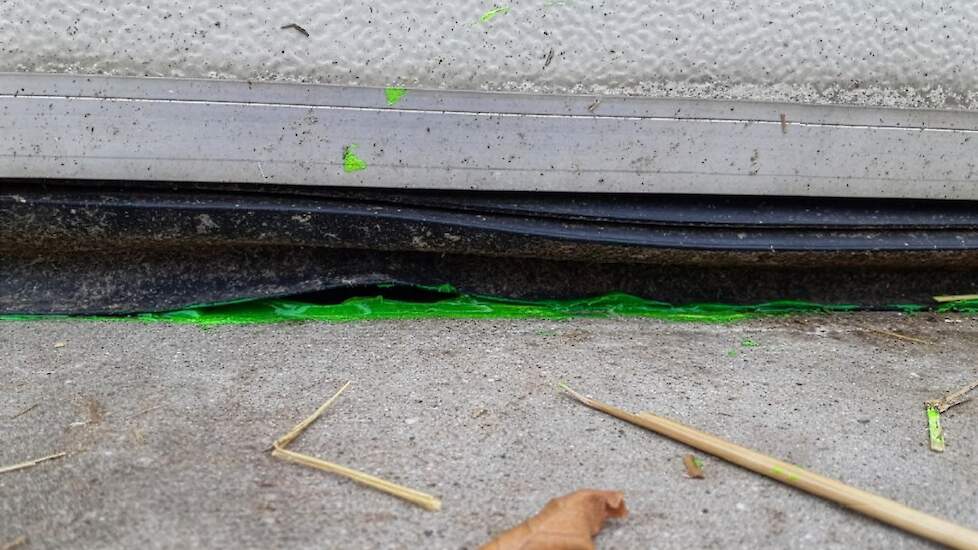 Groene fluorescentiegel bij een kromme rubber van een roldeur om waterlekkage naar binnen zichtbaar te maken.