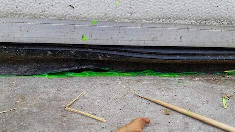 Groene fluorescentiegel bij een kromme rubber van een roldeur om waterlekkage naar binnen zichtbaar te maken.