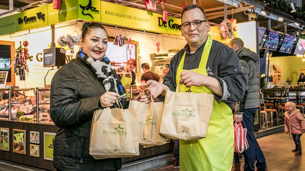 Slager Arie Jan Sterrenberg van De Groene Weg in de Markthal van Rotterdam overhandigt Ramona Eekhof producten van het 80.000ste varken.