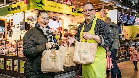 Slager Arie Jan Sterrenberg van De Groene Weg in de Markthal van Rotterdam overhandigt Ramona Eekhof producten van het 80.000ste varken.